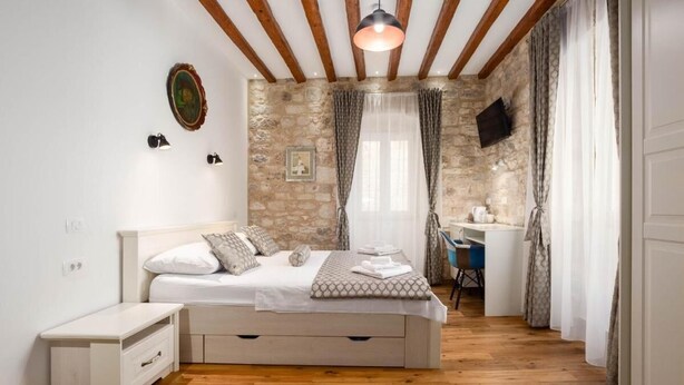 Een slaapkamer met een bed, nachtkastje en bureau met stoel.