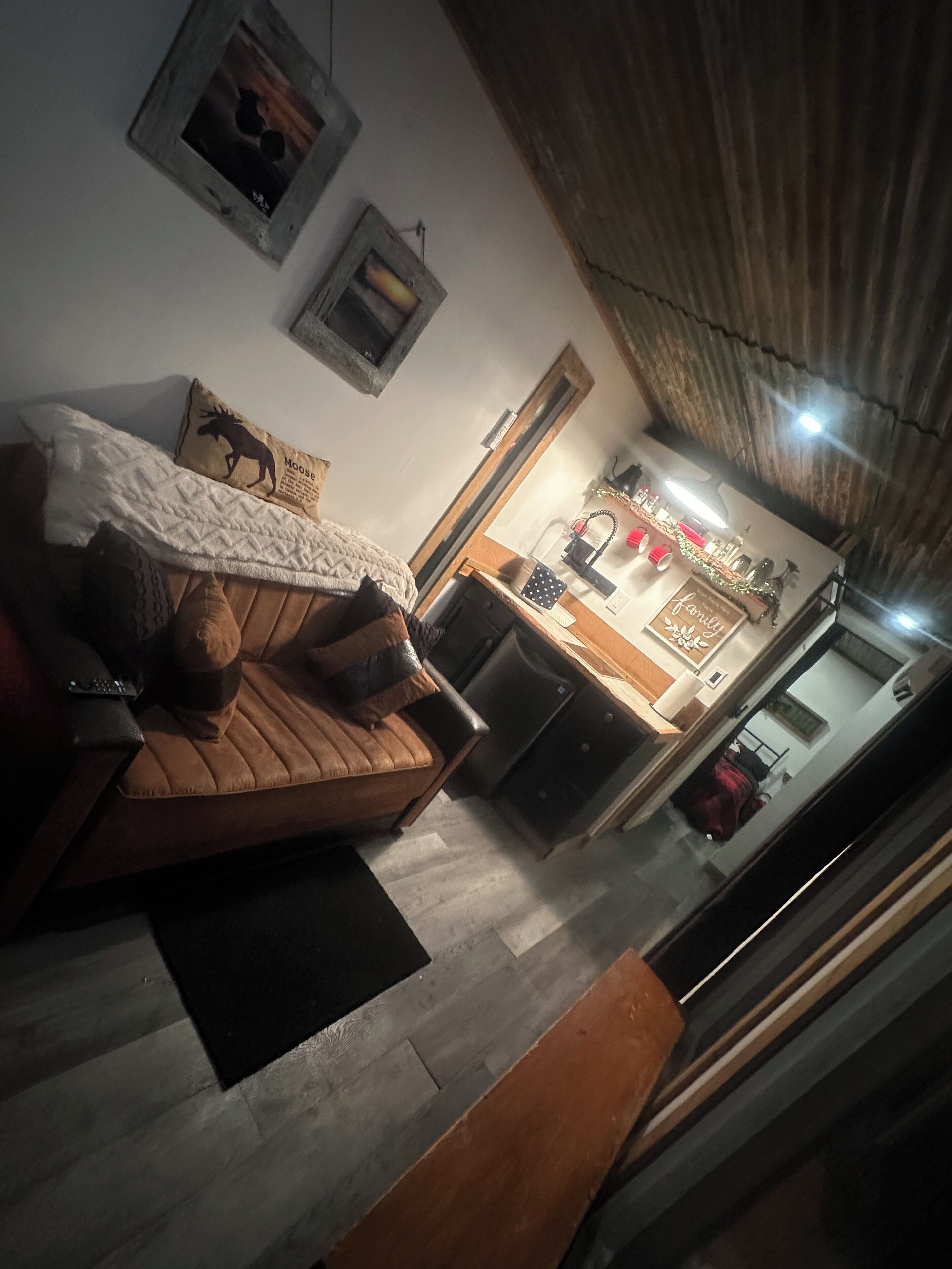 A cozy living room with a brown sofa, a coffee table, and a dining area with a kitchen counter and refrigerator.