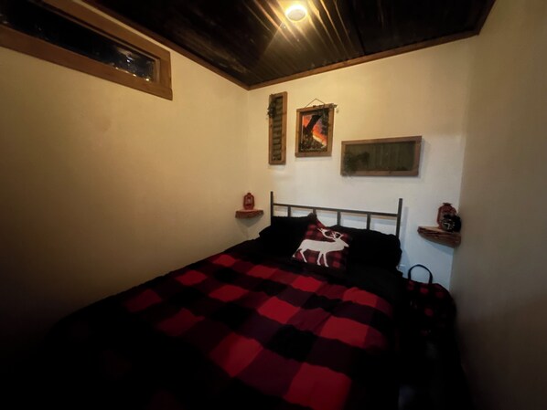 Een slaapkamer met een bed, een hoofdbord, een wandplank met een klok en een ingelijst kunstwerk.