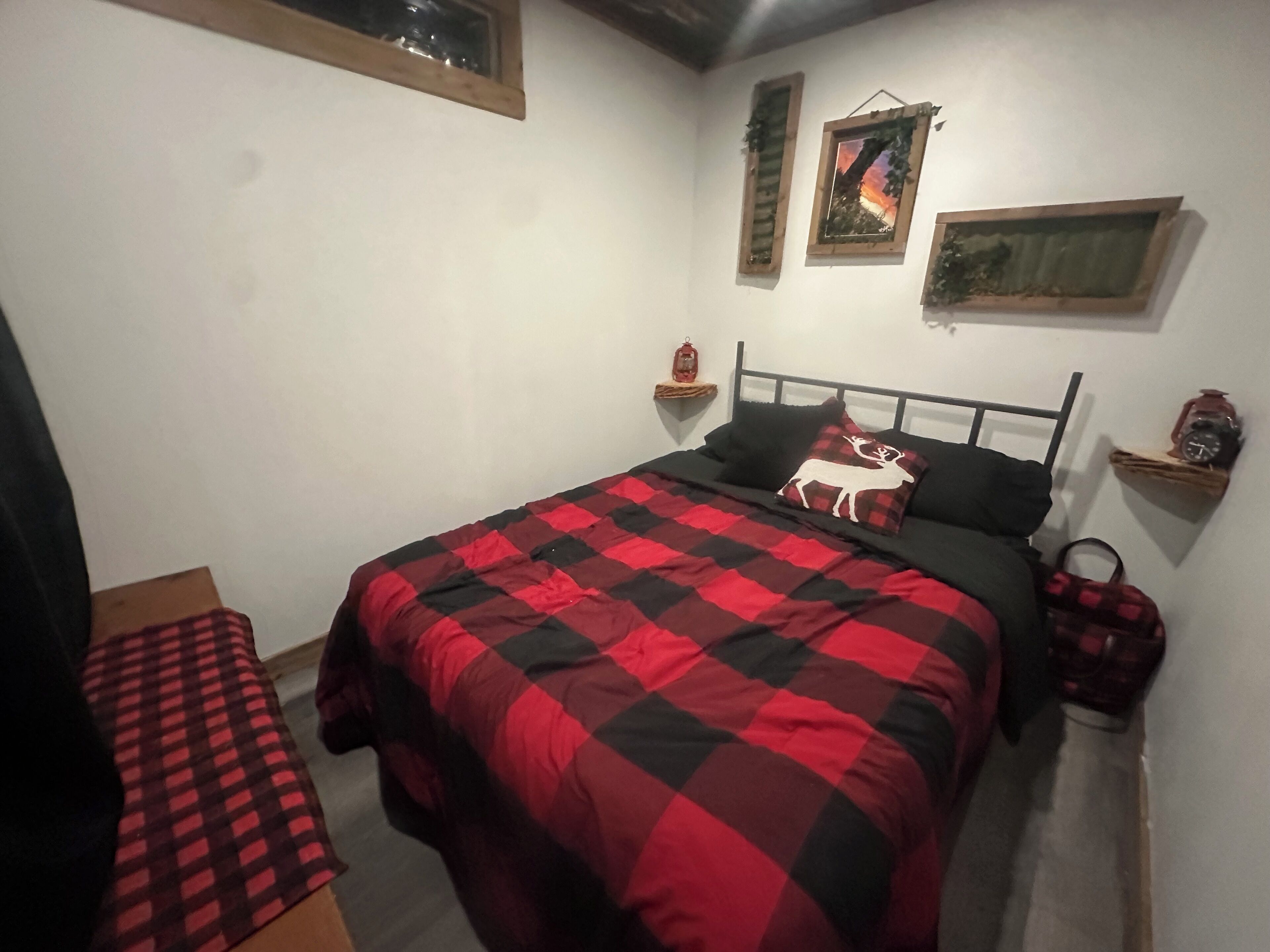 A bedroom with a bed, a nightstand, a window, and a wall-mounted shelf.