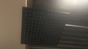 A room with a corrugated metal wall and a black panel with a grid pattern.