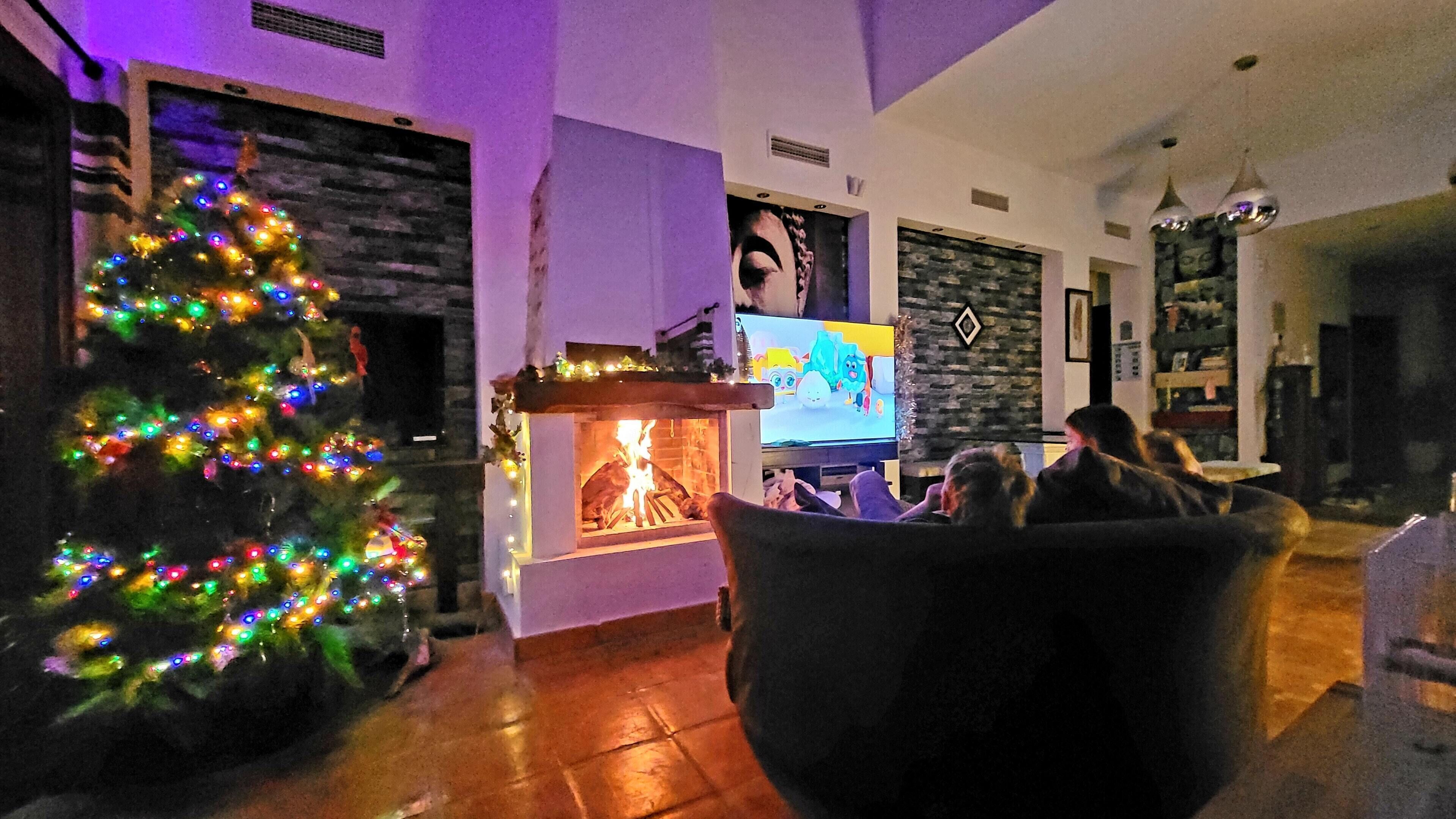 A cozy living room with a fireplace, a Christmas tree, and a flat-screen TV.