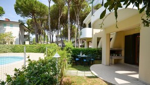 Un patio con piscina, mobiliario exterior y un edificio con balcones.
