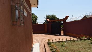 A building with a brick exterior, a gated entrance, and a small garden area with young plants.