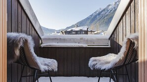 Un espace extérieur aménagé avec deux chaises, une terrasse en bois et une vue sur les montagnes.
