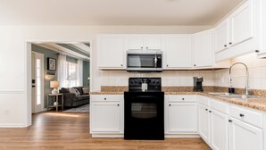 A kitchen with white cabinets, a black stove, a microwave, and a granite countertop. - Pet Friendly 3BR | Fenced Yard + Near RAFB (Warner Robins)