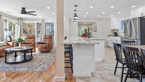 A spacious living room with a large window, a fireplace, and a dining area with a kitchen in the background. - Custer Gem, , Spacious Cabin with Hot Tub and Games (Custer)