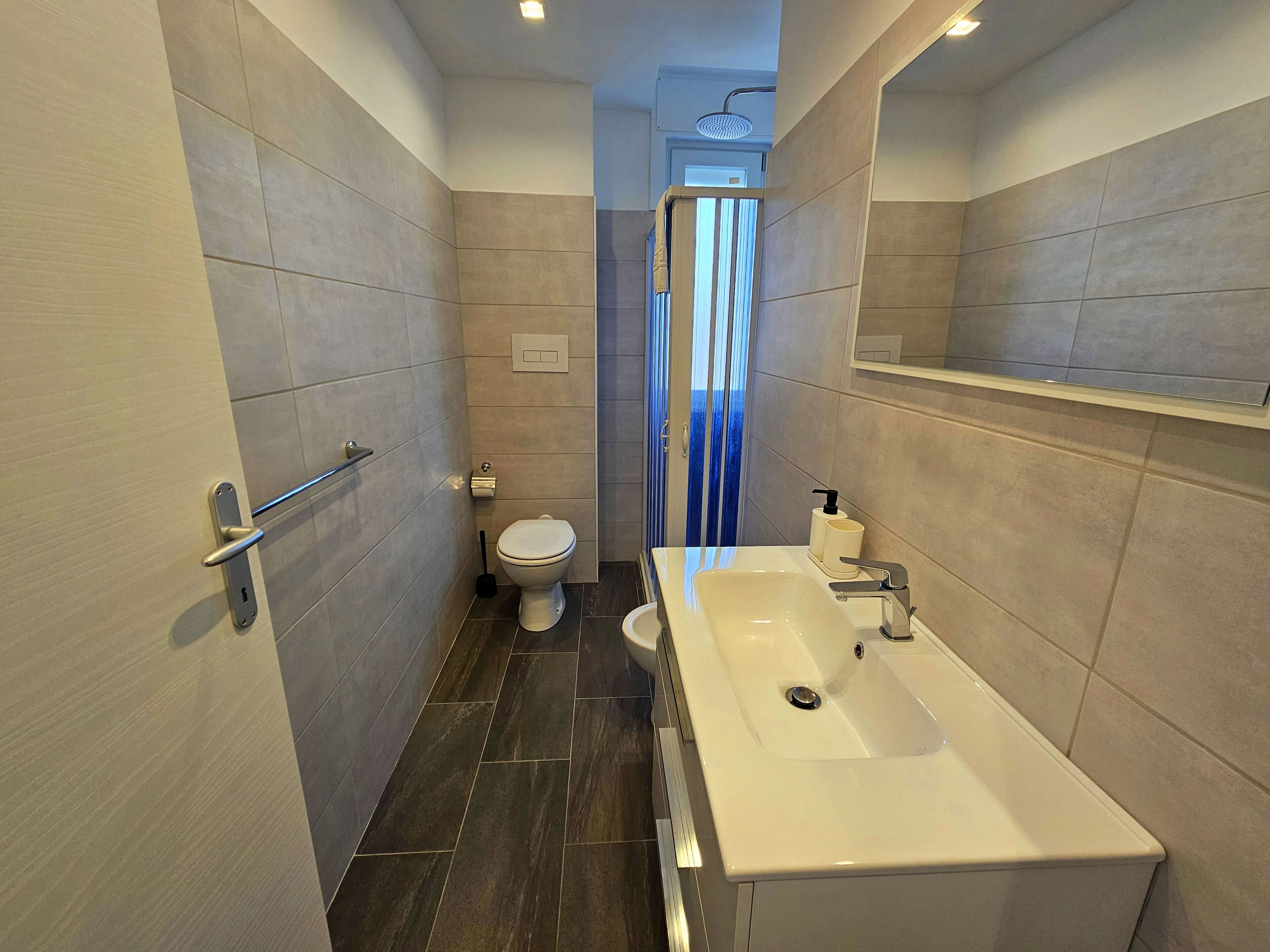 A modern bathroom with a toilet, sink, and shower.