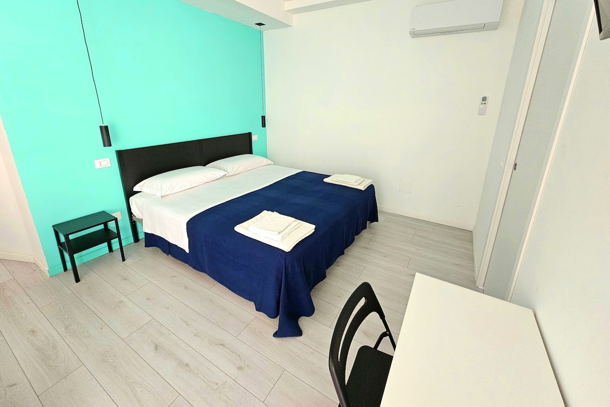 Une chambre à coucher avec un lit, une table de chevet et un bureau avec une chaise.