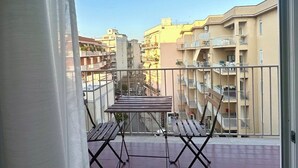 Un balcon avec une table et des chaises, donnant sur un quartier résidentiel composé de plusieurs immeubles.