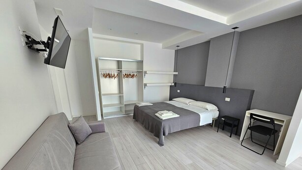 Une chambre à coucher moderne avec un lit, un canapé, un bureau et une armoire.