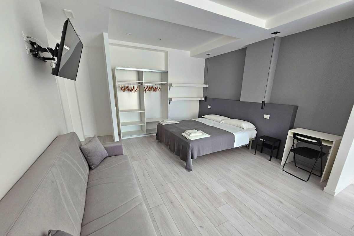 Une chambre à coucher moderne avec un lit, un canapé, un bureau et une armoire.