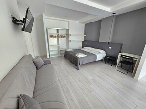 Un dormitorio moderno con cama, sofá, escritorio y armario.