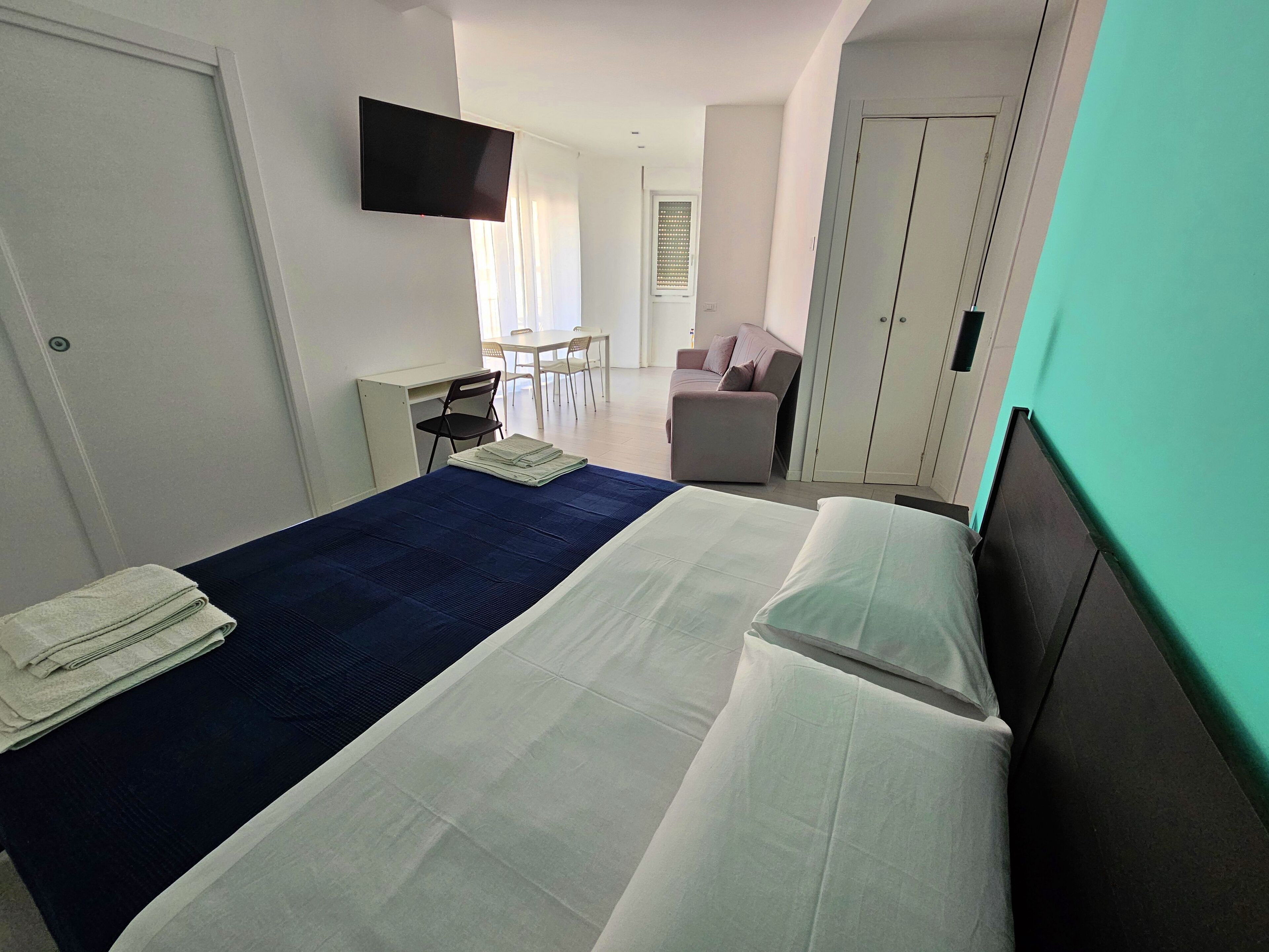 Une chambre d’hôtel comprenant un lit, un bureau, une chaise, une télévision et une armoire.