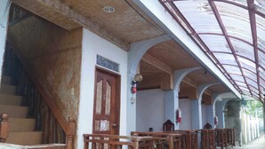 Un espace extérieur abrité, doté de bancs en bois et d’un escalier menant à un niveau supérieur.