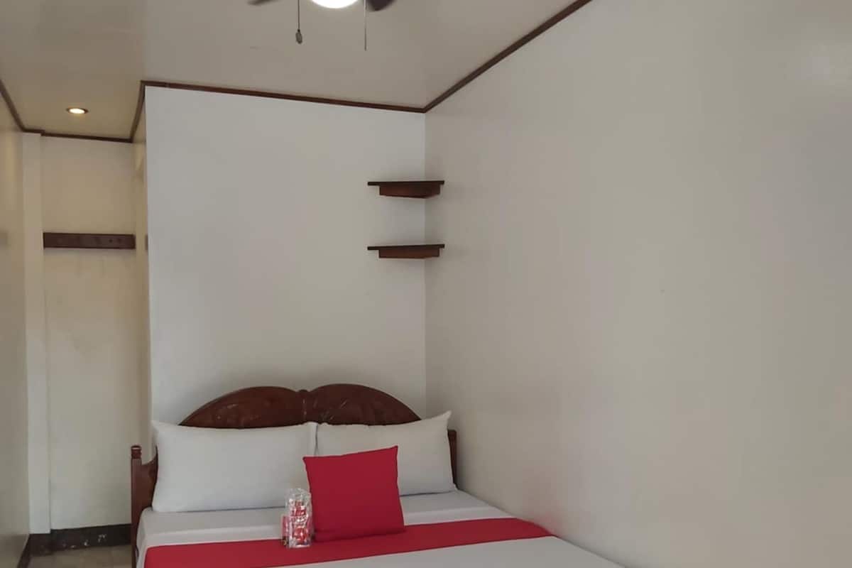 Quarto com cama, ventilador de teto e mesa de cabeceira.