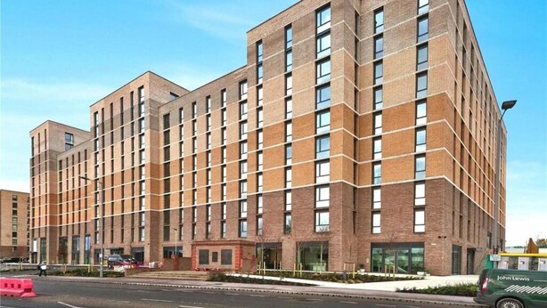 Ein mehrstöckiges Backsteingebäude mit einer rasterförmigen Fassade, großen Fenstern und einem Flachdach.