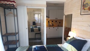 Un dormitorio con cama, literas de madera, kitchenette y baño.