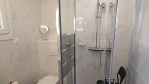 Un baño moderno con ducha envuelta en vidrio, inodoro y bañera.