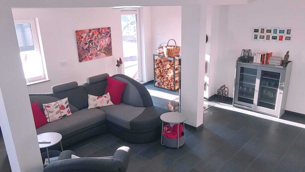 A modern living room with a grey sectional sofa, a small round table, and a cabinet with glass doors. - Quiet vacation home with lots of space (Masserberg)