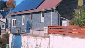 A house with a sloped roof, solar panels, and a red railing. - Quiet vacation home with lots of space (Masserberg)