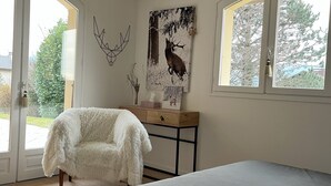 A bedroom with a large bed, a fluffy chair, a desk with a painting, and a chandelier. - Large house with ++ view, quiet, large garden, very close to lake and village (Menthon-Saint-Bernard)