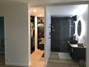 Ein modernes Badezimmer mit einem großen Spiegel, einem Waschbecken und einer Dusche.