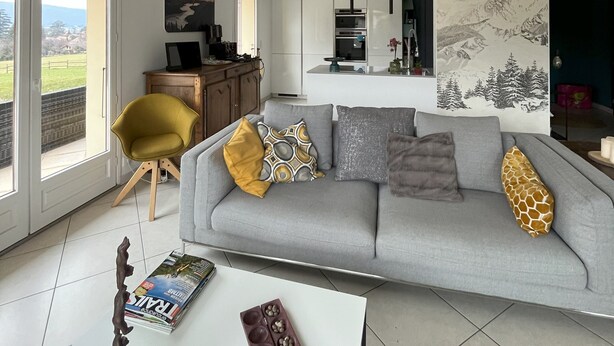 A spacious living area with a high ceiling, a grey sofa with patterned cushions, a yellow armchair, and a dining area in the background. - Large house with ++ view, quiet, large garden, very close to lake and village (Menthon-Saint-Bernard)