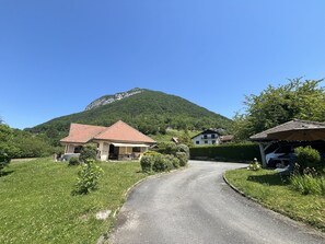 Eine ländliche Straße, die zu Häusern führt, mit einem Berg im Hintergrund.