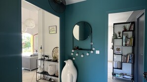 A modern living room with teal walls, a white ceramic penguin sculpture, a round mirror, and a bookshelf. - Large house with ++ view, quiet, large garden, very close to lake and village (Menthon-Saint-Bernard)