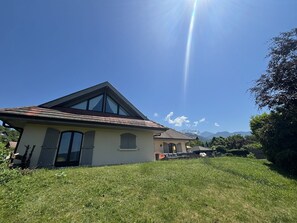 Ein Haus mit geneigtem Dach, großen Fenstern und einem Rasen.