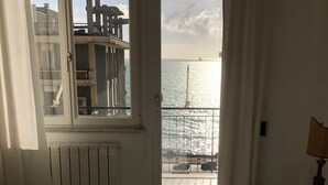 A room with a bed, a window with a view of the sea, and a radiator. - Sea view apartment in the city center, 3 minutes from the station and port (Salerno)