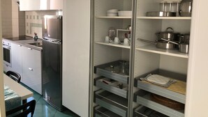 A modern kitchen with stainless steel appliances, white cabinetry, and open shelving for storage. - Sea view apartment in the city center, 3 minutes from the station and port (Salerno)