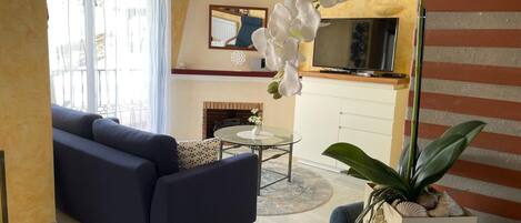 Una sala de estar con sofá, mesa de centro, televisor y chimenea.