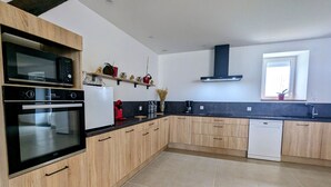 Een moderne keuken met houten kastjes, een ingebouwde oven, magnetron en vaatwasser.