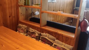 A wooden table with a bench, a shelf with a lamp, and a hanging fire extinguisher.