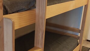 A bunk bed with a wooden frame and a dark mattress.