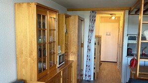 A narrow hallway with wooden cabinets and a dining area.