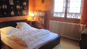 Una habitación de madera con una cama, una estantería y una ventana.