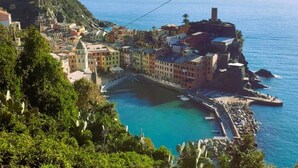 A coastal town with buildings along the waterfront, a clear blue sea, and a cable car line.