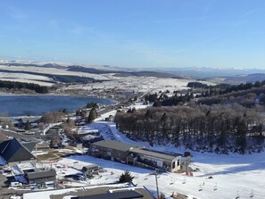 Ein Skigebiet mit einer Seilbahn, einem Gebäude mit der Aufschrift 'TELEPHERIQUE de la Perdonx' und einem See im Hintergrund.