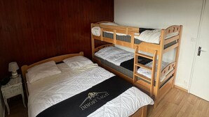 A bunk bed room with a wooden headboard, a nightstand with a lamp, and a door. - Apartment at the slopes with private garage (Besse-et-Saint-Anastaise-Super Besse)