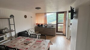 A compact kitchen with a dining area, wooden cabinets, and a view of the outdoors. - Apartment at the slopes with private garage (Besse-et-Saint-Anastaise-Super Besse)