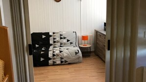 A room with a bed, a small table with a lamp, a dresser, and a radiator. - Apartment at the slopes with private garage (Besse-et-Saint-Anastaise-Super Besse)