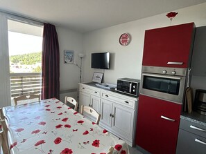 Eine kleine Küche mit Esstisch, Mikrowelle, Backofen und Fernseher.