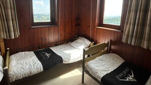 Ein Zimmer mit zwei Holzbettstühlen, einem Fenster mit Blick und einer kleinen Ablagefläche.