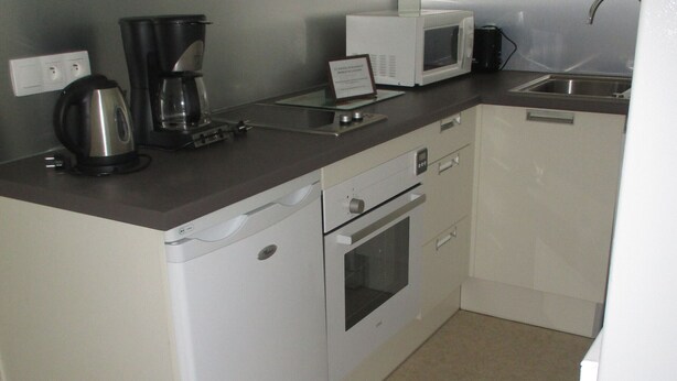 A compact kitchen with a coffee maker, microwave, and a dishwasher.