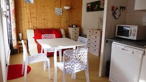 A compact kitchen with white appliances, a dining table, and chairs.