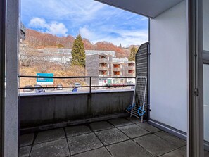 Ein Balkon mit Blick auf ein Gebäude mit mehreren Balkonen, einem Schild und geparkten Autos.