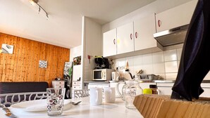 A modern kitchen with white cabinets, a wooden accent wall, and various appliances.